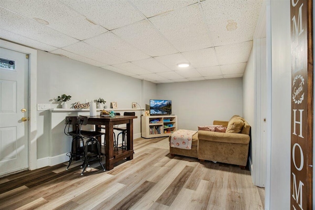 living room with a paneled ceiling and light hardwood / wood-style flooring