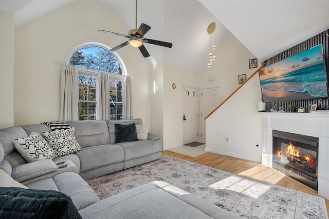 living room with ceiling fan, high vaulted ceiling, and light hardwood / wood-style flooring