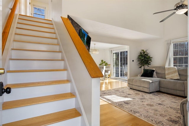 staircase with wood-type flooring, ceiling fan, and a high ceiling