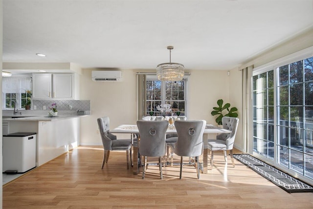 dining area featuring a notable chandelier, sink, a wall mounted AC, and light wood-type flooring