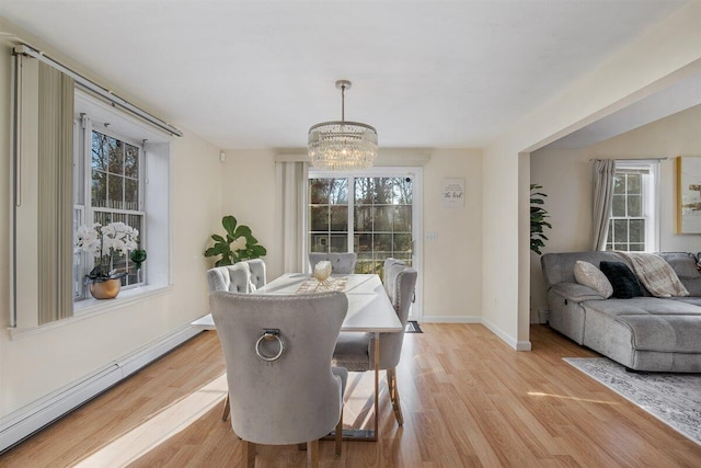 dining area with a baseboard heating unit, a notable chandelier, and light hardwood / wood-style floors