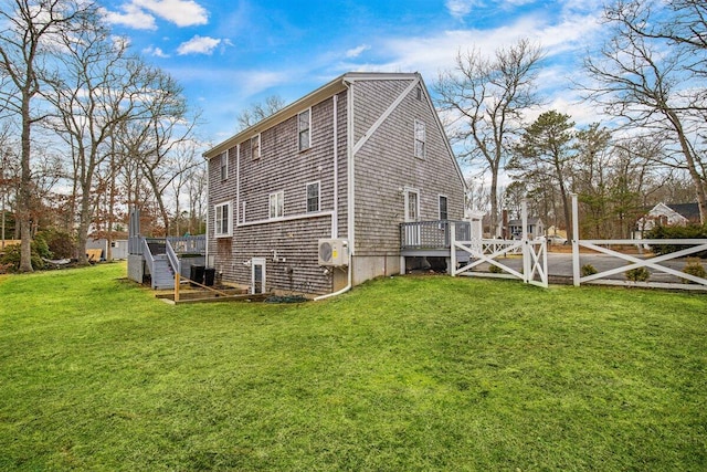 rear view of house with a deck, a lawn, and ac unit