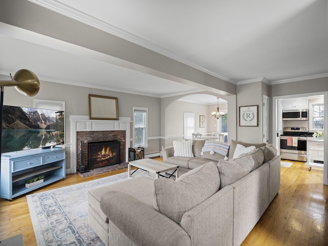 17 Edwards Rd, Hyannis, MA 02601 - living area with crown molding, arched walkways, a fireplace, a chandelier, and light wood-style floors