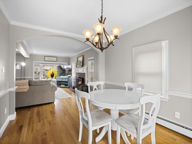 17 Edwards Rd, Hyannis, MA 02601 - dining space featuring crown molding, arched walkways, wood finished floors, and a lit fireplace