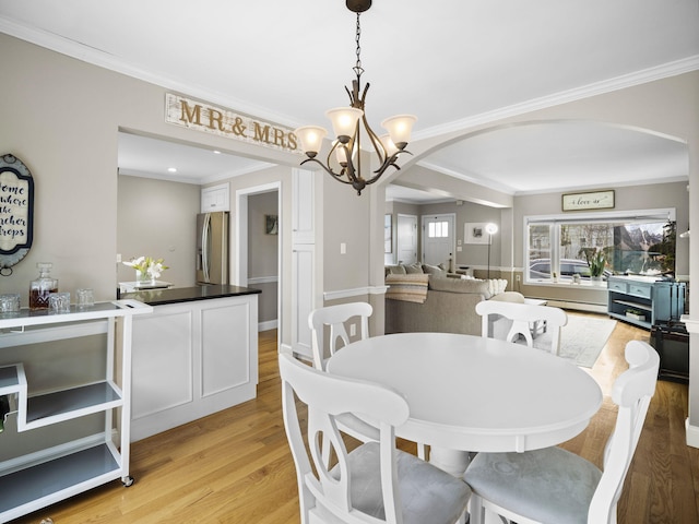 17 Edwards Rd, Hyannis, MA 02601 - dining room with crown molding, arched walkways, a chandelier, light wood-style flooring, and a baseboard radiator
