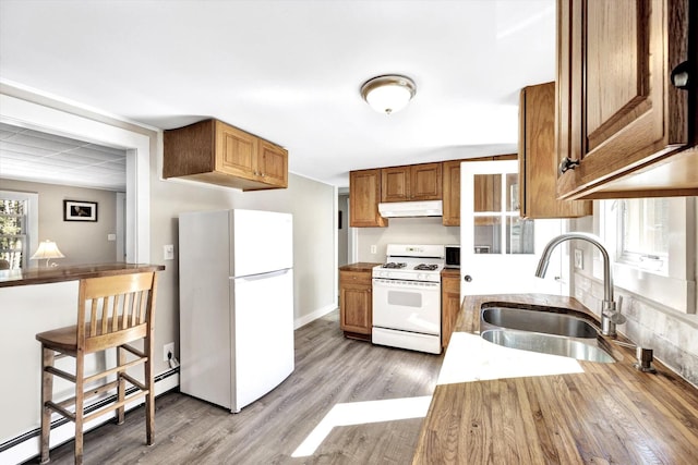 kitchen with sink, white appliances, a baseboard heating unit, and light hardwood / wood-style floors