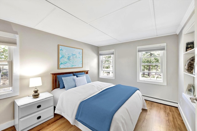 bedroom with light hardwood / wood-style flooring and a baseboard heating unit