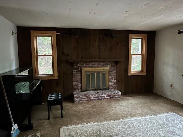 carpeted living room with wood walls and a fireplace