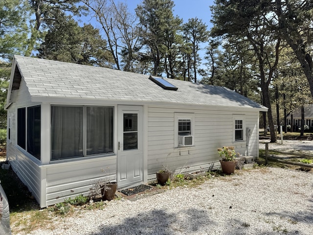 rear view of property featuring cooling unit and roof with shingles