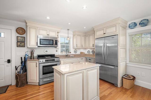 kitchen featuring a sink, stainless steel appliances, light wood-type flooring, and cream cabinetry