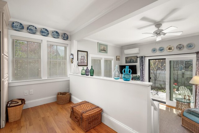 interior space featuring an AC wall unit, ornamental molding, baseboards, and plenty of natural light