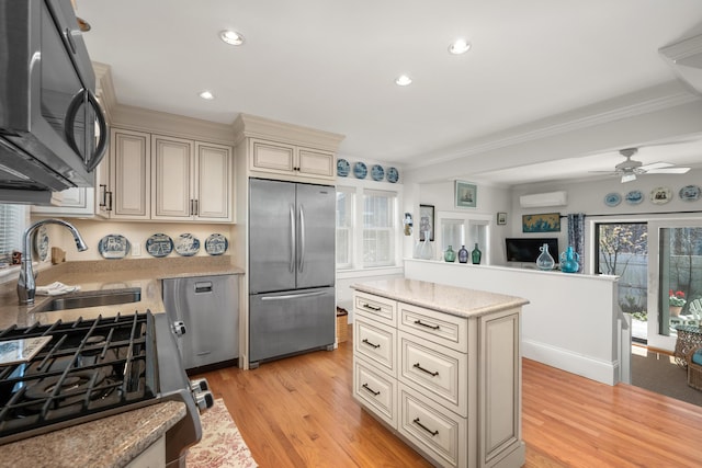 kitchen featuring cream cabinets, crown molding, a sink, light wood-style floors, and stainless steel appliances