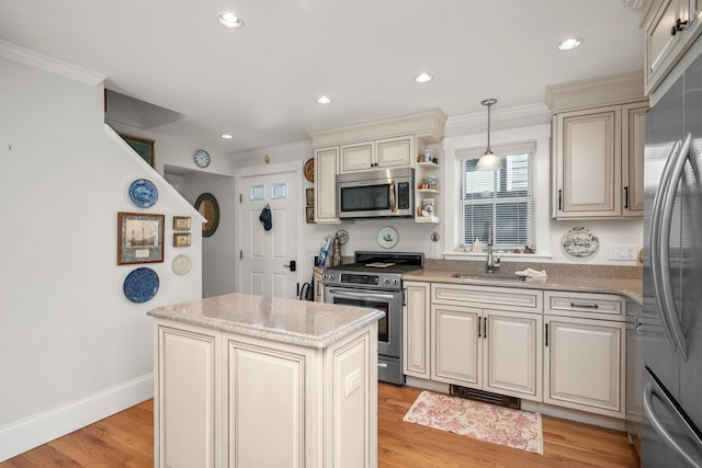 kitchen featuring cream cabinetry, appliances with stainless steel finishes, a sink, and a center island