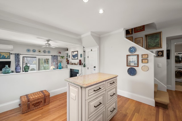 kitchen with crown molding, a fireplace, light wood-style floors, an AC wall unit, and stacked washing maching and dryer