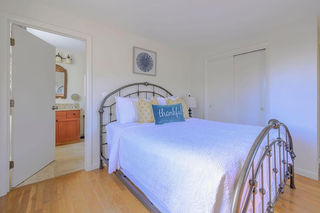 bedroom featuring a closet, connected bathroom, and light hardwood / wood-style flooring