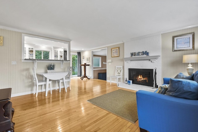 living room with a brick fireplace, ornamental molding, and wood-type flooring