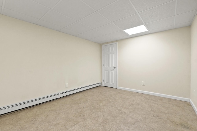 carpeted spare room featuring a drop ceiling and a baseboard heating unit