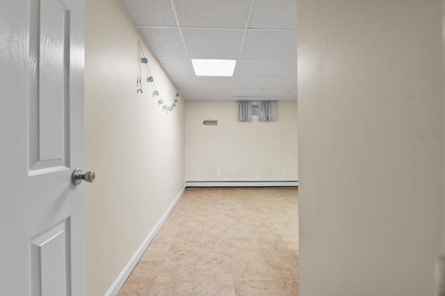 basement with a baseboard radiator and a paneled ceiling