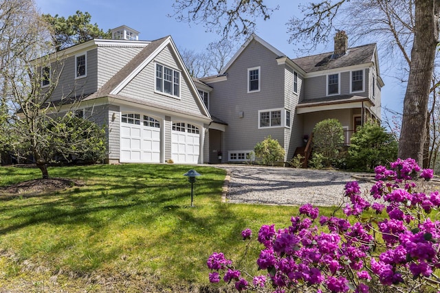 shingle-style home with an attached garage, driveway, a front lawn, a chimney, and roof with shingles