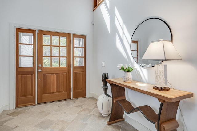 entryway with stone finish flooring, baseboards, and a high ceiling