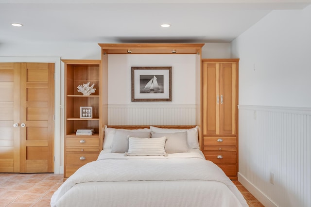 bedroom featuring a wainscoted wall, light tile patterned floors, and recessed lighting