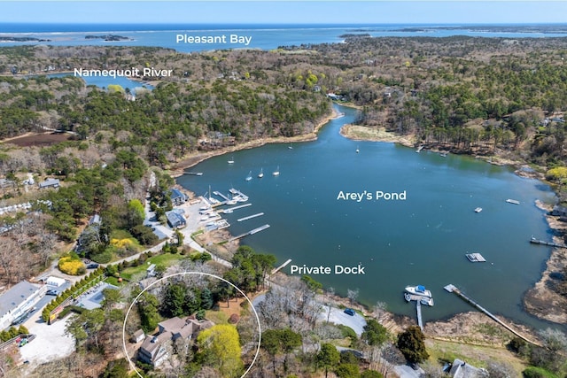 aerial view of property and surrounding area featuring a nearby body of water and a heavily wooded area