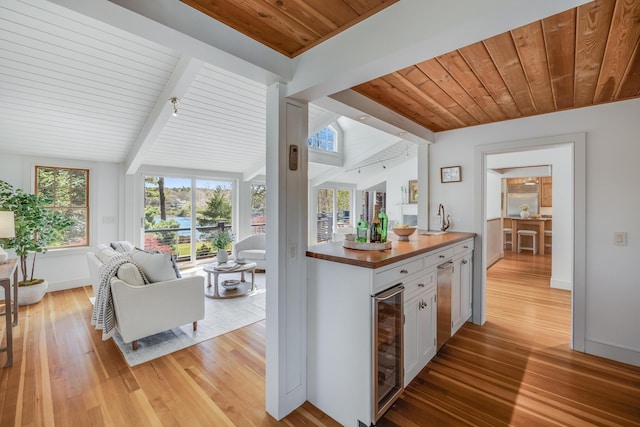 kitchen with wooden ceiling, light wood finished floors, beverage cooler, white cabinetry, and open floor plan