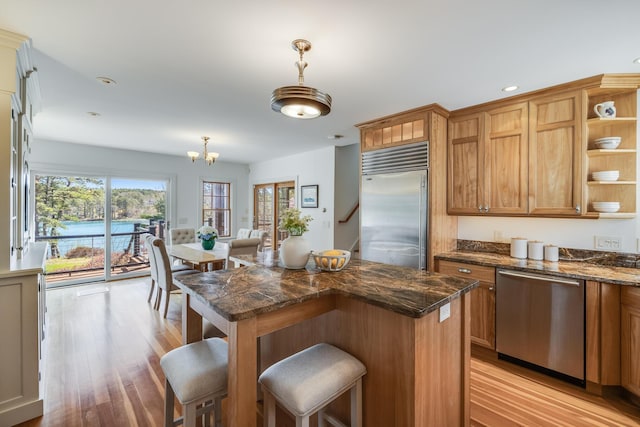 kitchen with stainless steel appliances, light wood-style floors, a breakfast bar area, open shelves, and recessed lighting