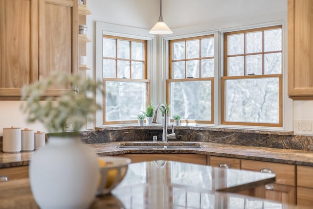 kitchen featuring a sink, dark stone countertops, and decorative light fixtures
