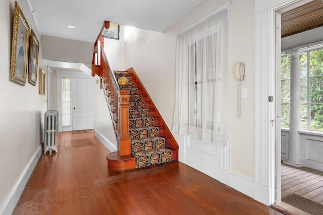 stairs with radiator heating unit, a healthy amount of sunlight, and wood-type flooring