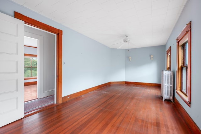 unfurnished room featuring radiator heating unit, dark hardwood / wood-style floors, and ceiling fan