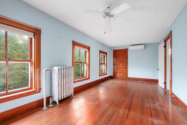 spare room featuring ceiling fan, an AC wall unit, radiator, and hardwood / wood-style floors