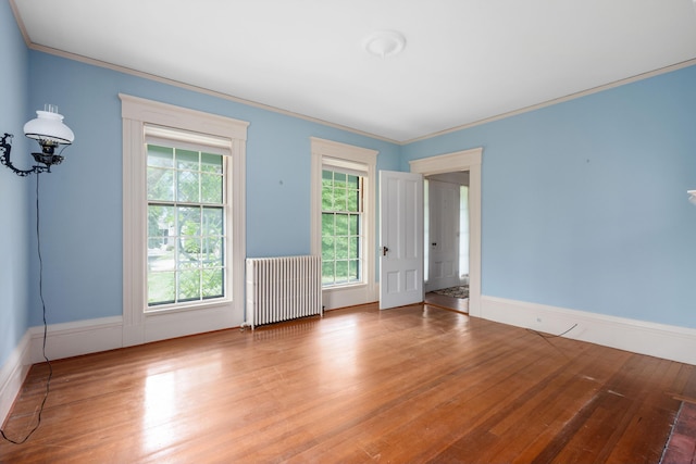 empty room featuring radiator heating unit, hardwood / wood-style floors, and crown molding