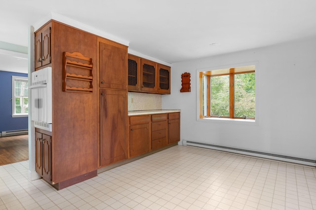 kitchen with white oven, backsplash, and baseboard heating