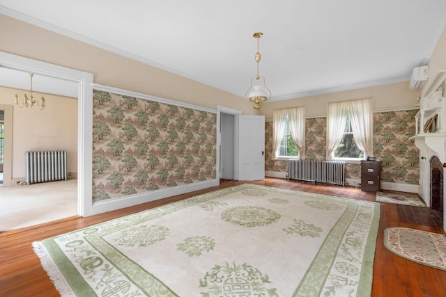 living area featuring a wall unit AC, radiator heating unit, an inviting chandelier, and wood-type flooring