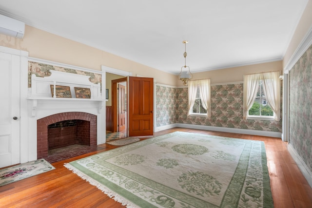 unfurnished living room with hardwood / wood-style flooring, a brick fireplace, ornamental molding, and a wall mounted air conditioner