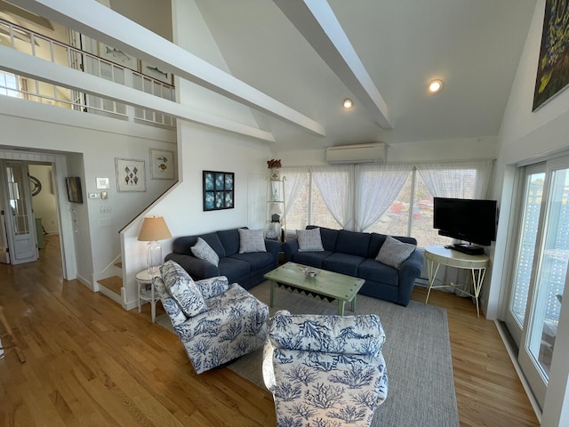 living room with an AC wall unit, a wealth of natural light, hardwood / wood-style flooring, and high vaulted ceiling