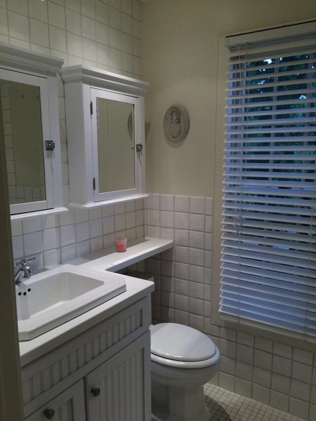 bathroom with tile walls, toilet, vanity, and tile patterned flooring