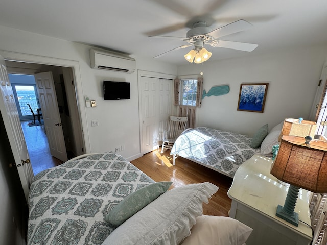 bedroom with ceiling fan, wood-type flooring, a closet, and a wall mounted AC