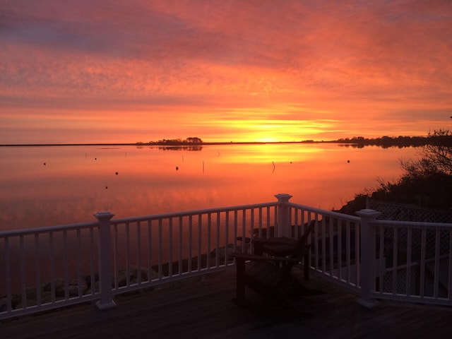 deck at dusk featuring a water view