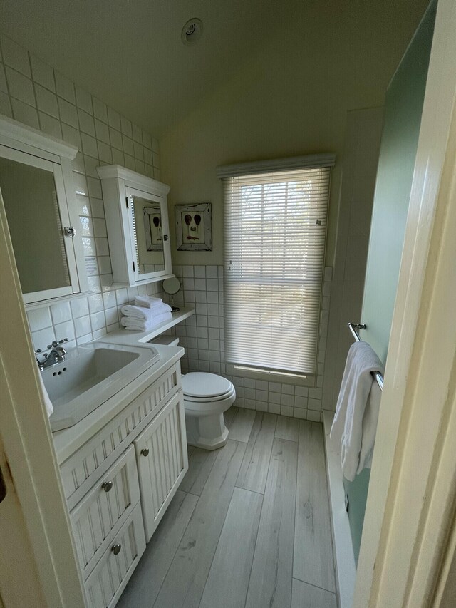 bathroom with vanity, backsplash, tile walls, toilet, and hardwood / wood-style flooring