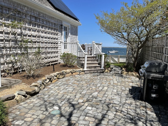 view of patio with a water view and a grill