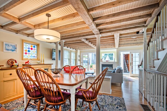 351A Commercial St Unit A1, Provincetown, MA 02657 - dining area with light wood finished floors, a fireplace, stairway, coffered ceiling, and a wooden ceiling with exposed beams
