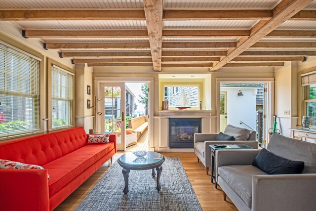 351A Commercial St Unit A1, Provincetown, MA 02657 - living area featuring beamed ceiling, plenty of natural light, a glass covered fireplace, and light wood-style flooring