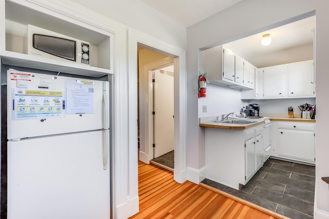 kitchen with sink, white cabinetry, white refrigerator, and dark hardwood / wood-style flooring