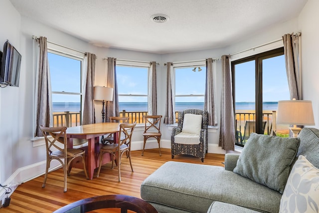 living room featuring a water view, a textured ceiling, and wood-type flooring