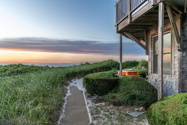 yard at dusk featuring a balcony and a water view