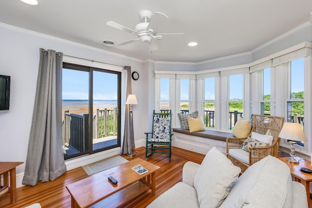 living room featuring wood-type flooring, a healthy amount of sunlight, and crown molding