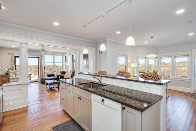 kitchen featuring white dishwasher, decorative columns, white cabinets, decorative light fixtures, and dark stone countertops