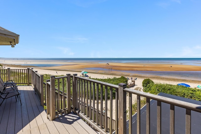 wooden deck featuring a water view and a view of the beach